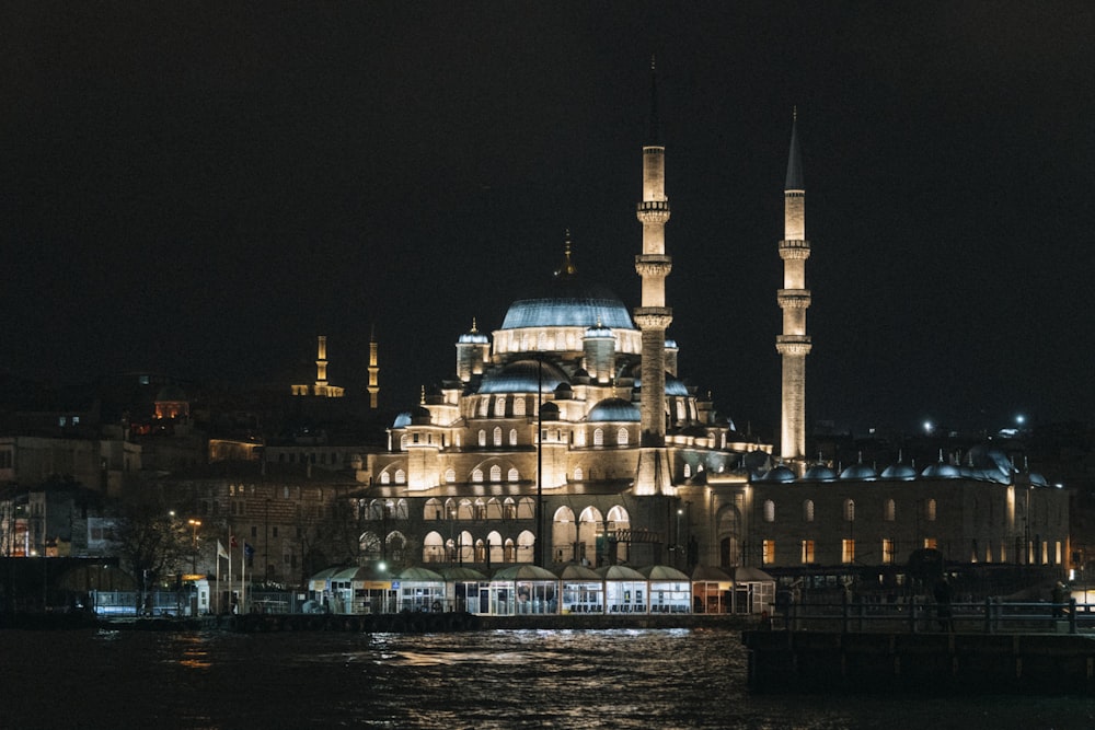 a large building lit up at night by a body of water