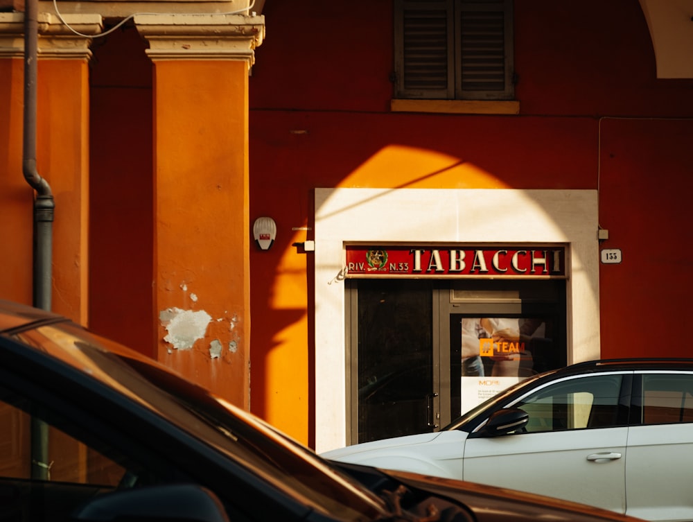 a white car parked in front of a red building