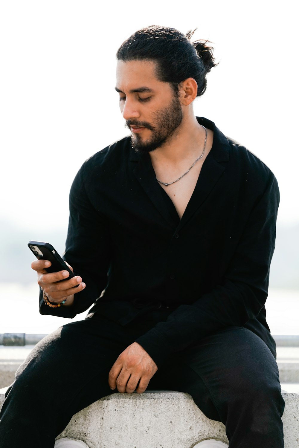 a man sitting on a wall looking at his cell phone