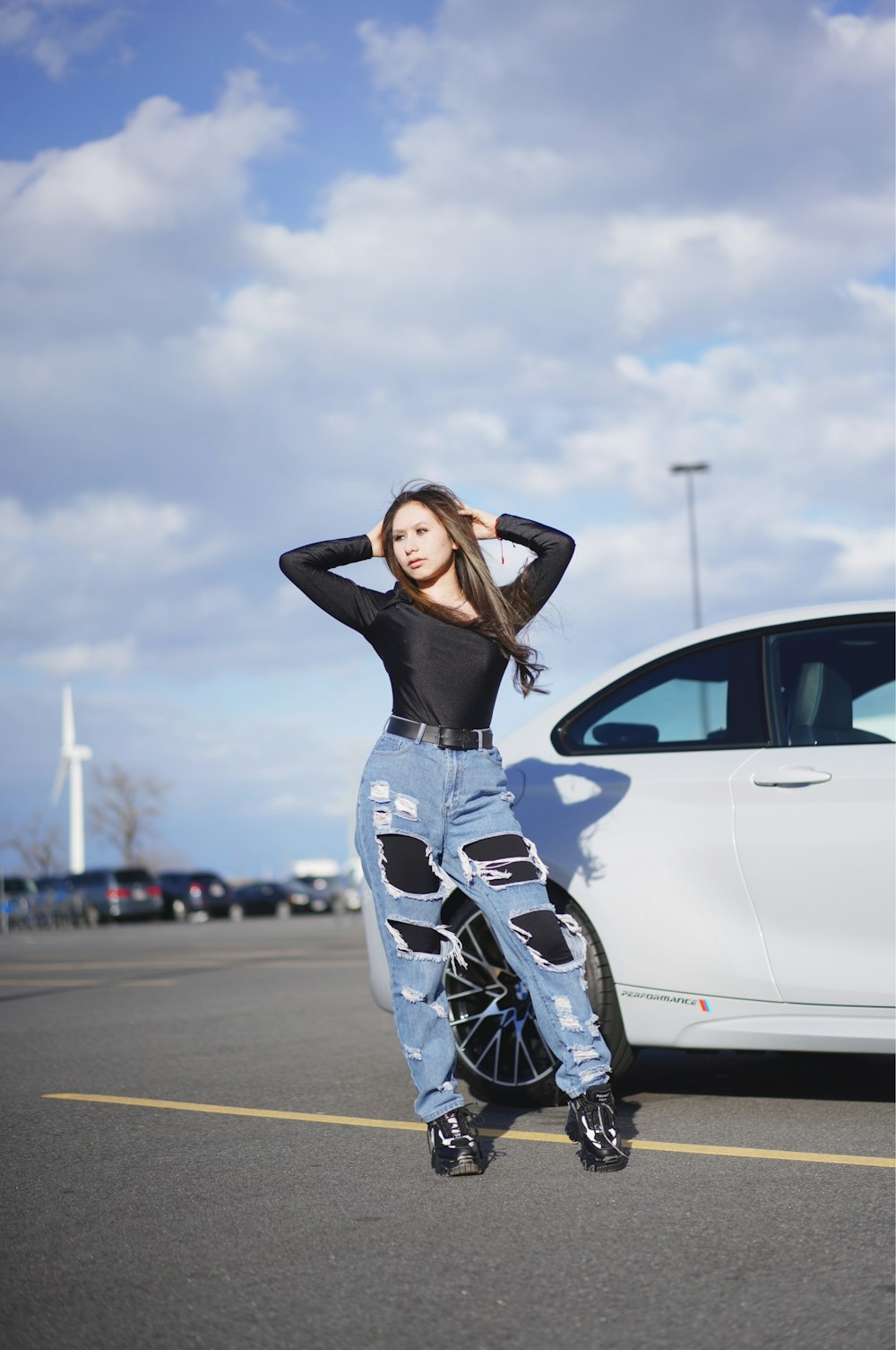 a woman standing in a parking lot next to a car