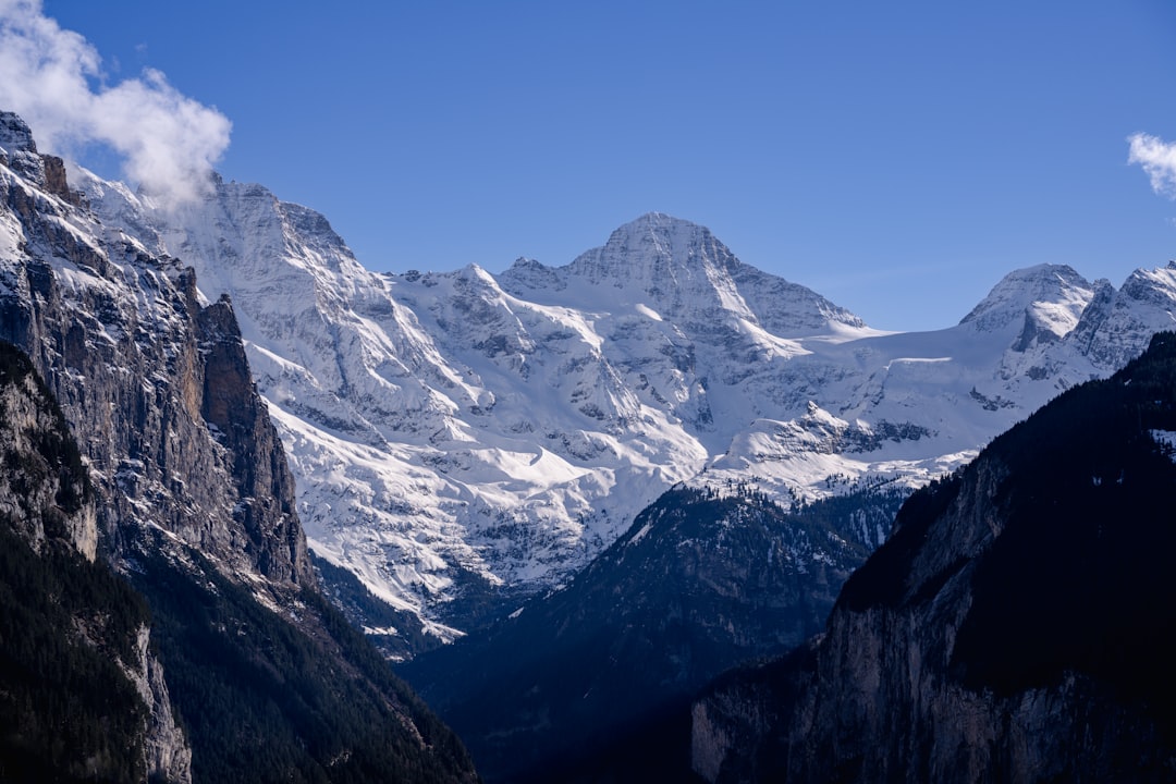 a mountain range with snow covered mountains in the background, The Lauterbrunnen Valley and the Alps.