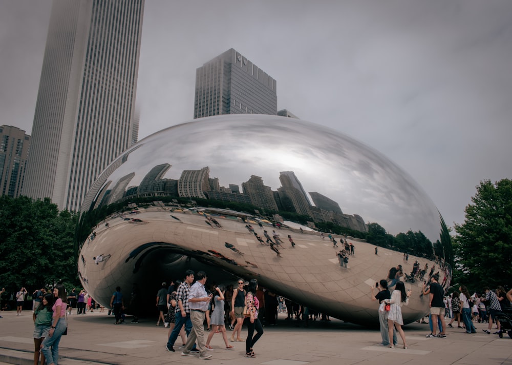 a group of people standing in front of a large shiny object