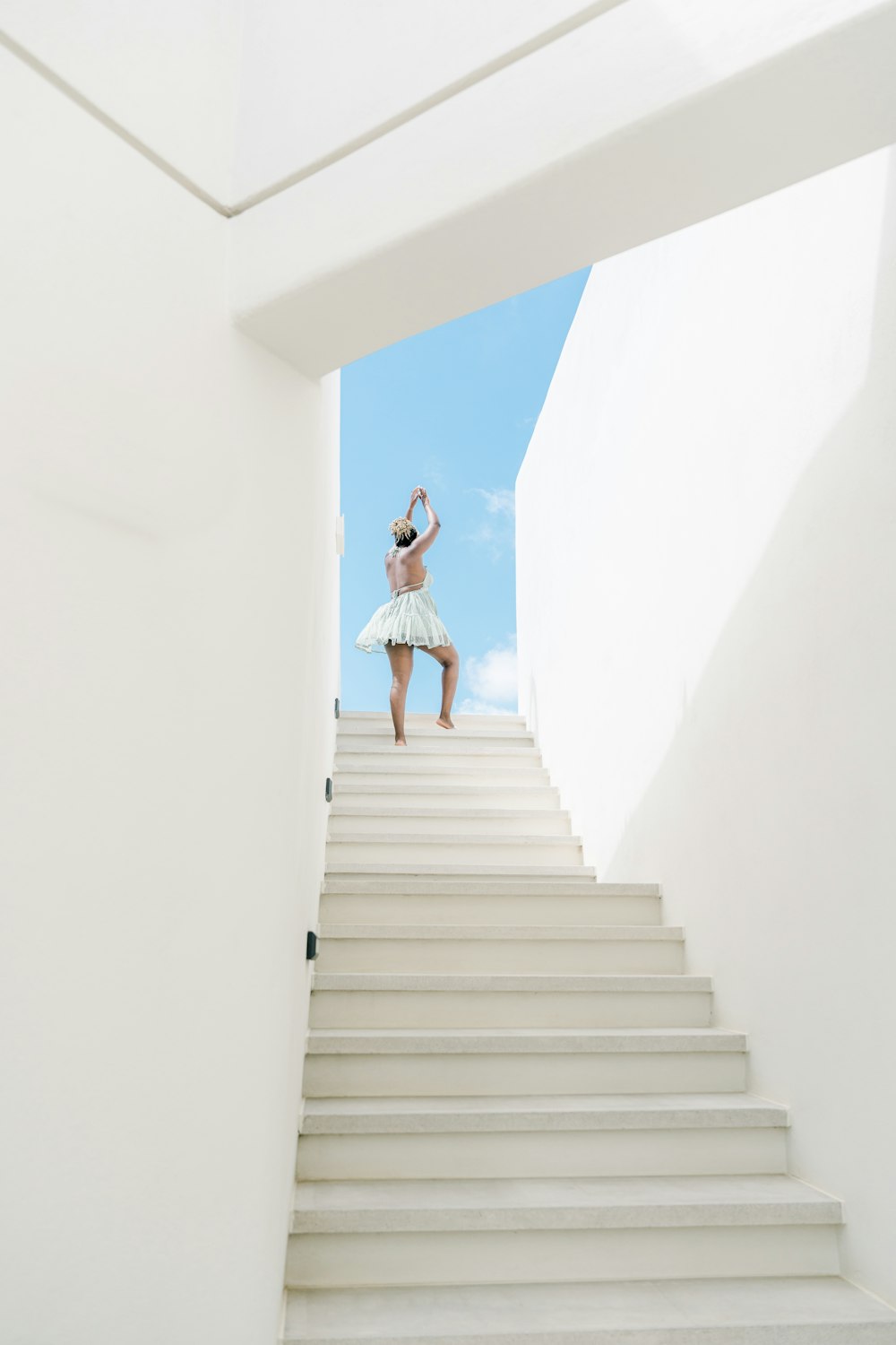 a woman in a white dress is walking down a set of stairs