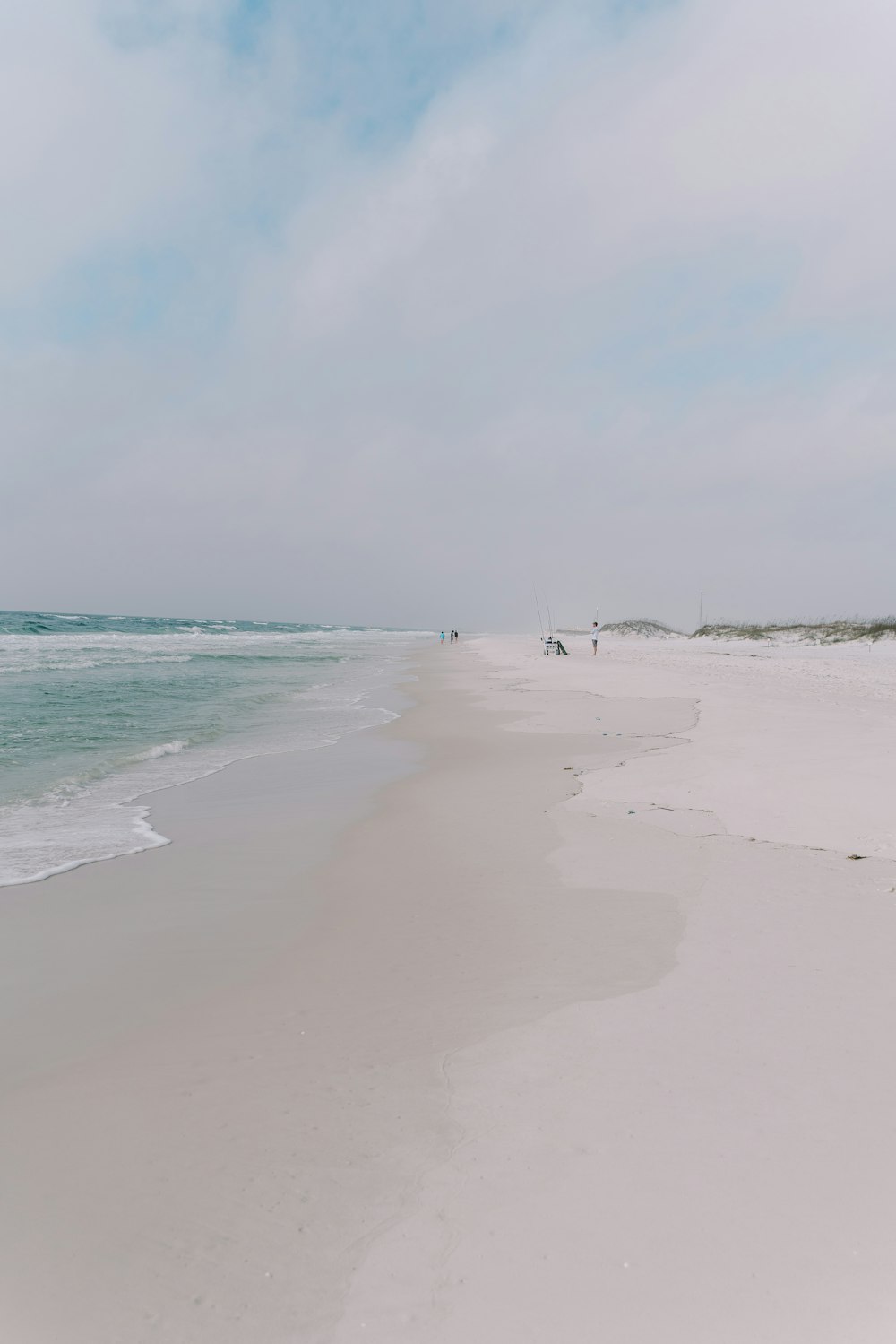 a sandy beach with a few people walking on it