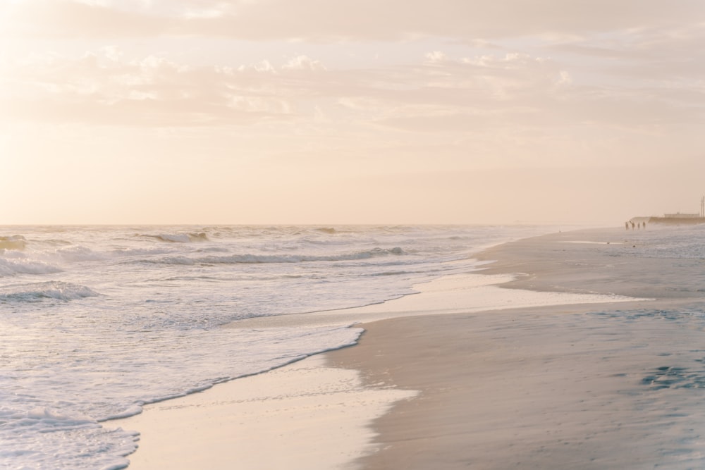 a sandy beach next to the ocean under a cloudy sky