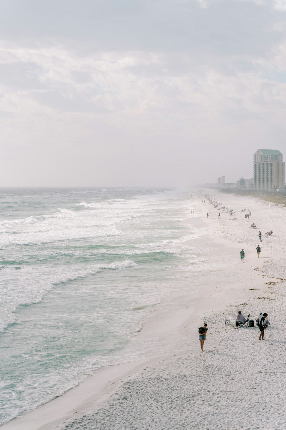 a group of people walking along a beach next to the ocean