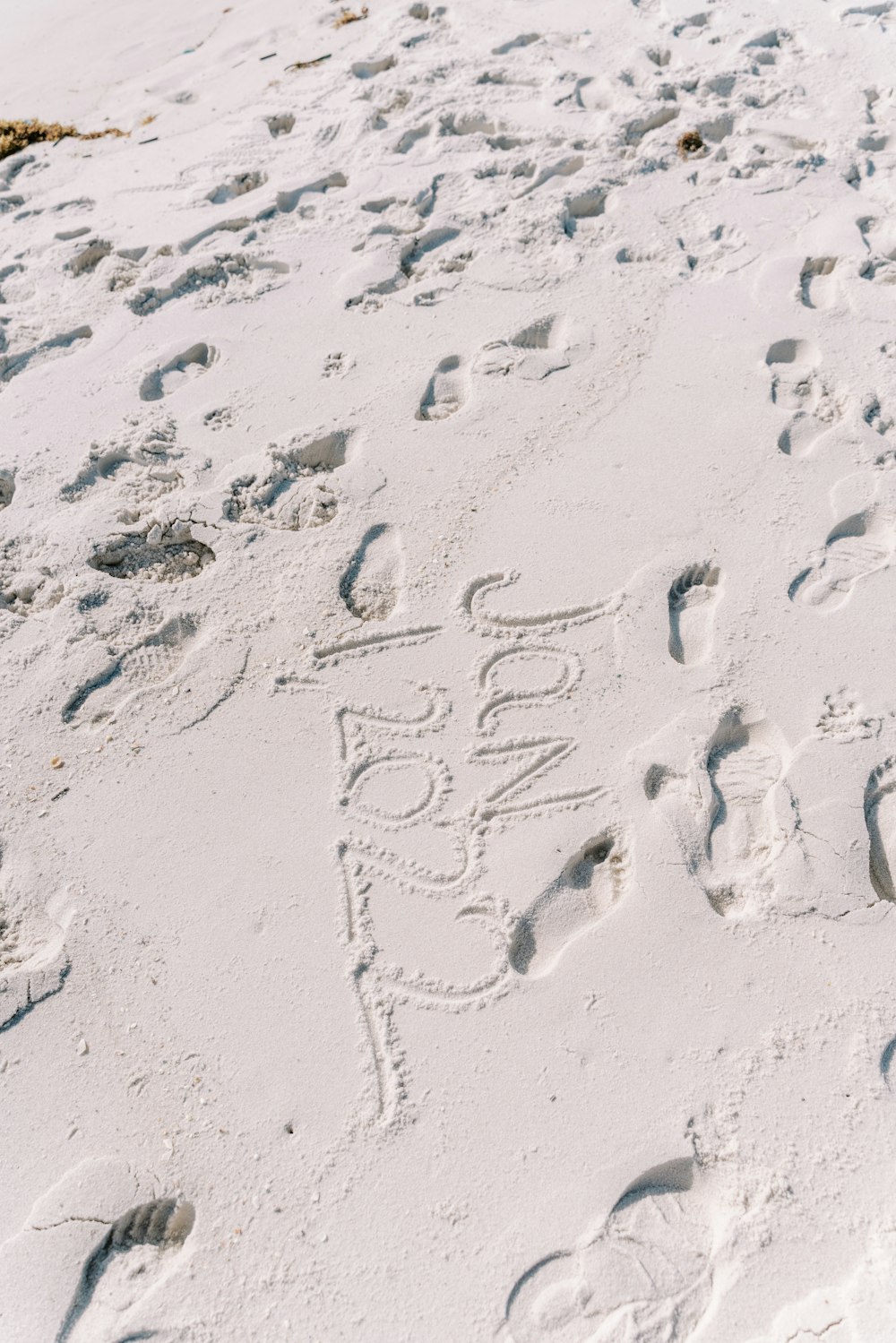 a sandy beach covered in footprints and writing