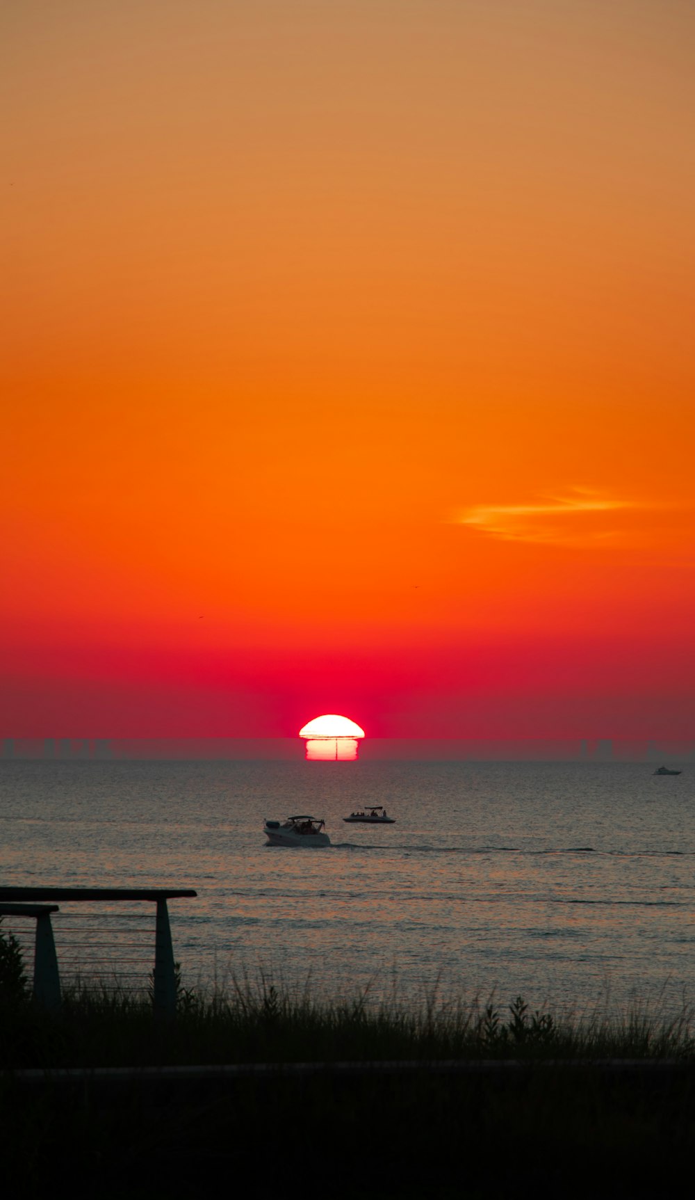 a sunset over the ocean with boats in the water