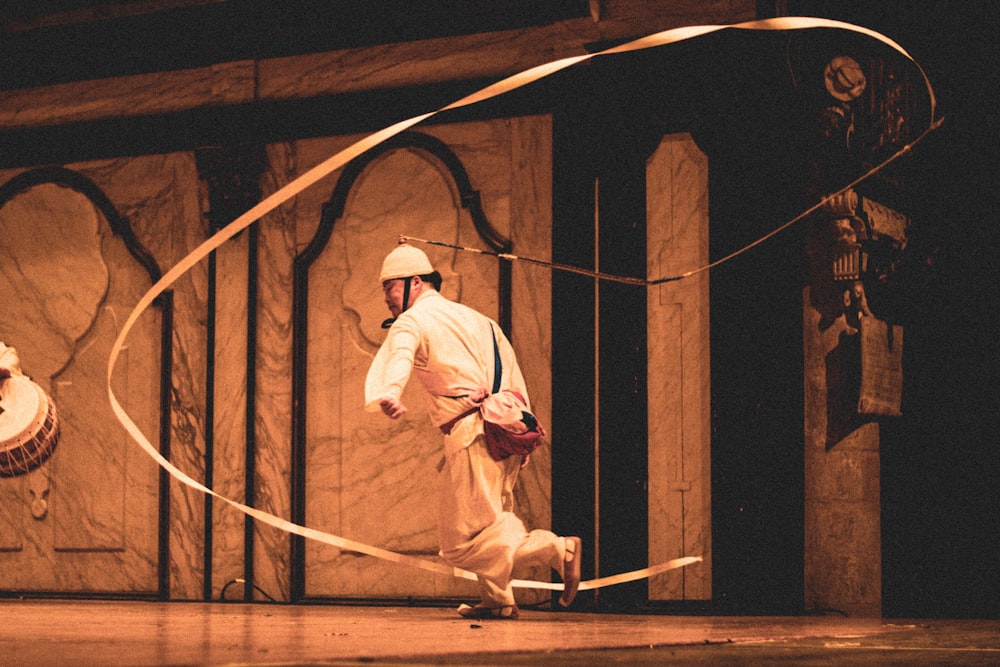 a man in a white outfit is performing with a hoop