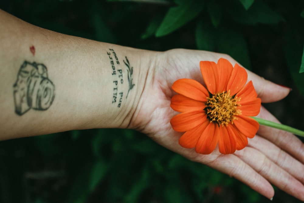 a person with a tattoo on their arm holding a flower
