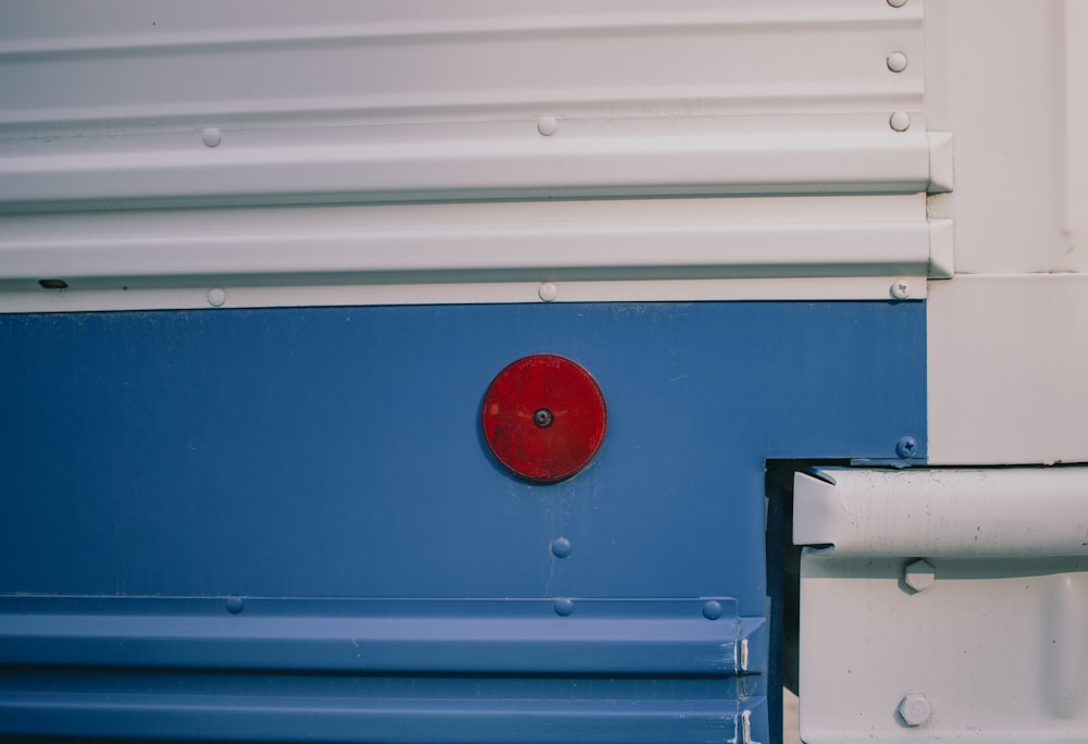 un botón rojo en el costado de un camión azul y blanco