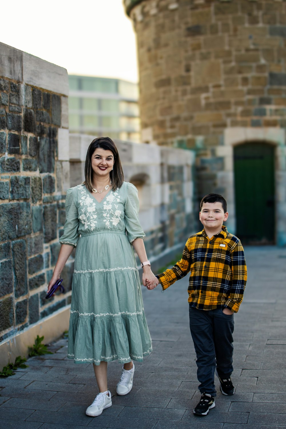 a woman holding the hand of a young boy