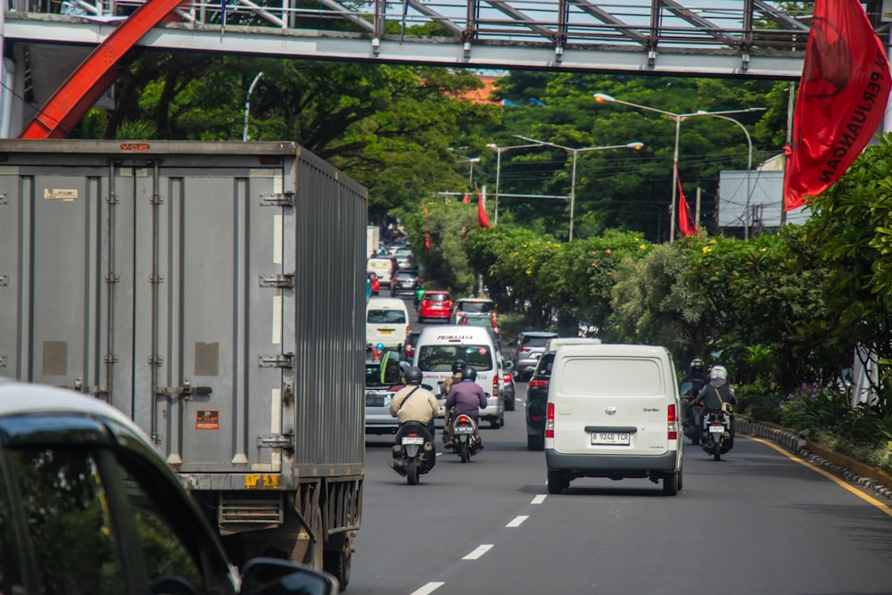 um grupo de carros dirigindo por uma rua ao lado de uma ponte