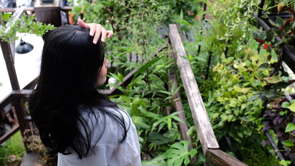 a woman is combing her long hair in a garden