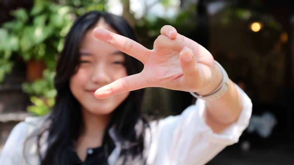 a woman making a peace sign with her hand