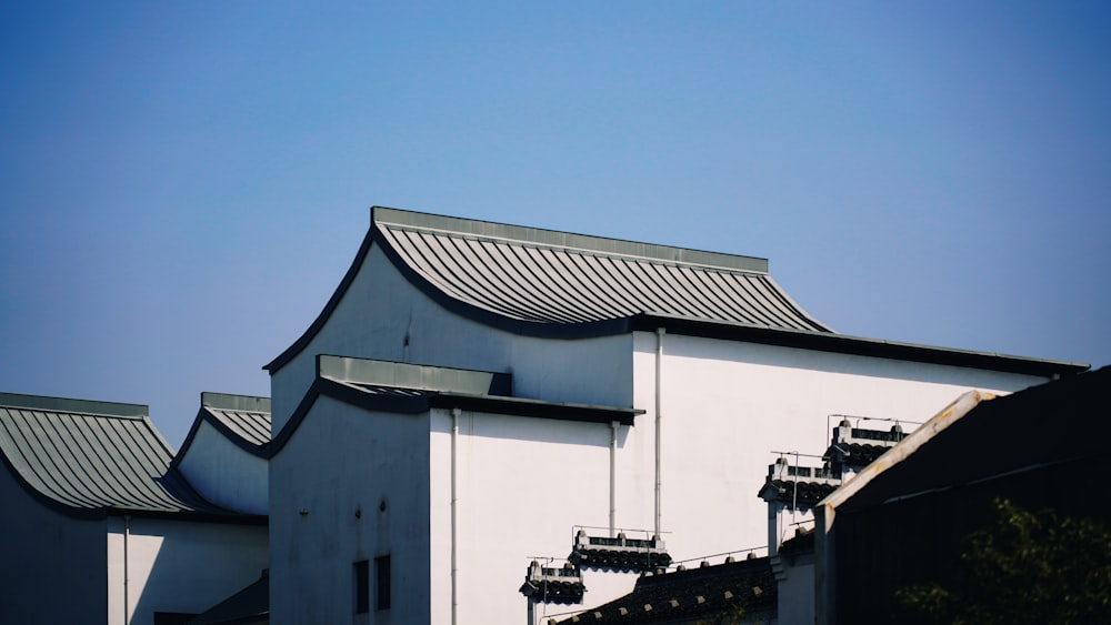 a white building with a black roof and a blue sky