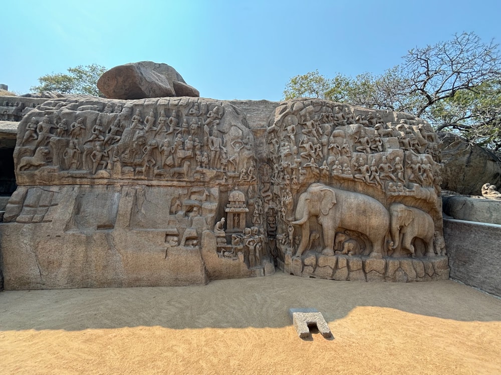 a stone wall with carvings of elephants and people on it