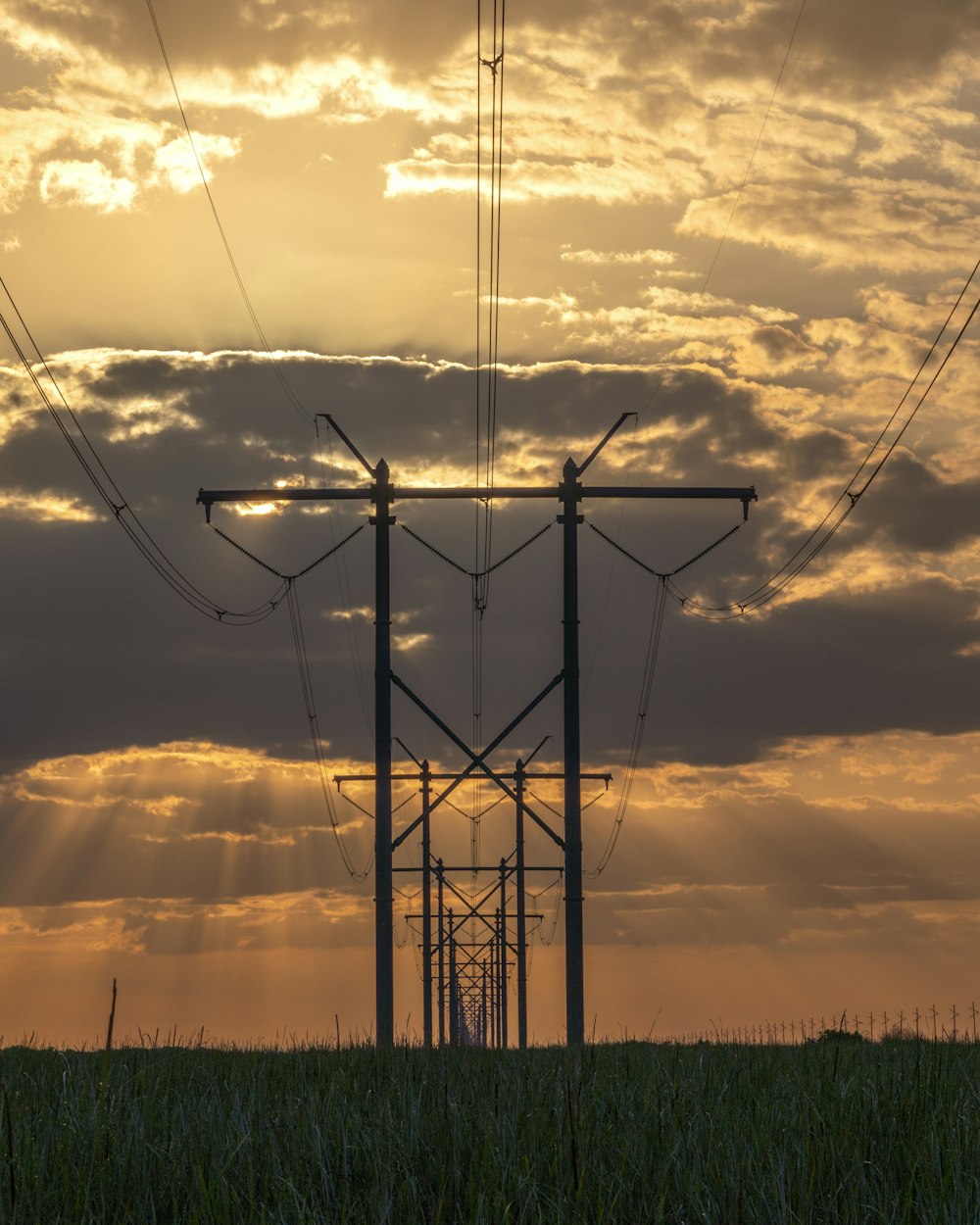 the sun is shining through the clouds behind power lines