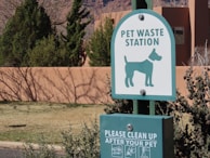 a green and white sign that says pet waste station