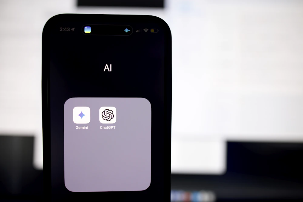 iPhone showing an AI folder containing Gemini and ChatGPT apps