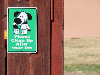 a sign on a wooden fence that says please clean up after your pet