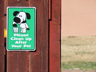 a sign on a wooden fence that says please clean up after your pet