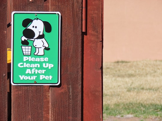 a sign on a wooden fence that says please clean up after your pet