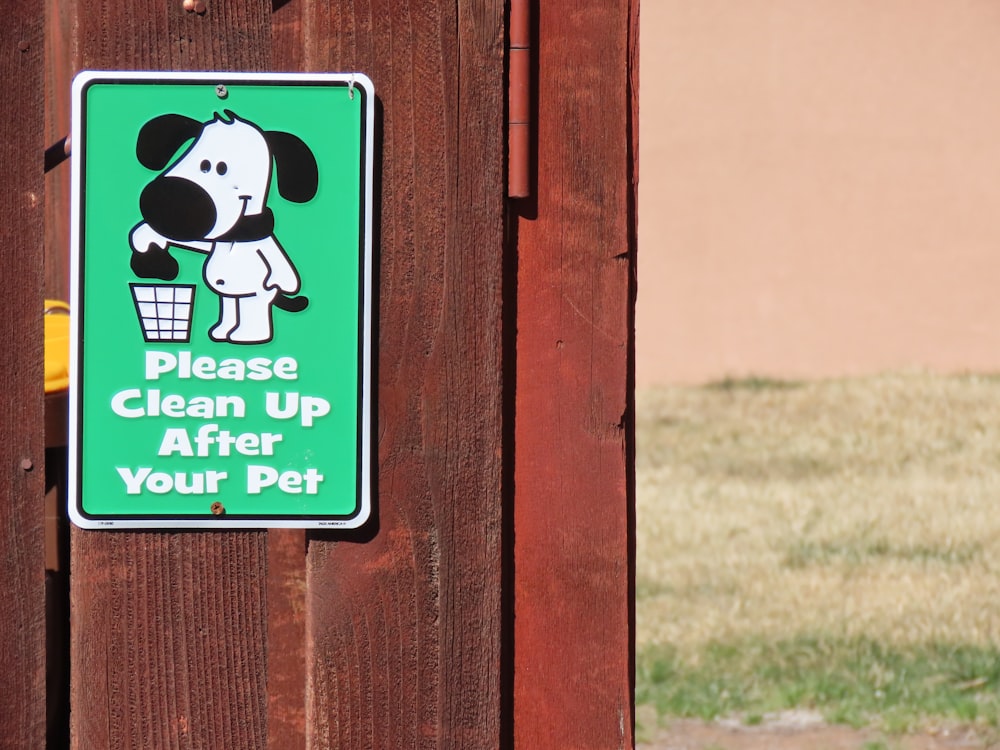 a sign on a wooden fence that says please clean up after your pet