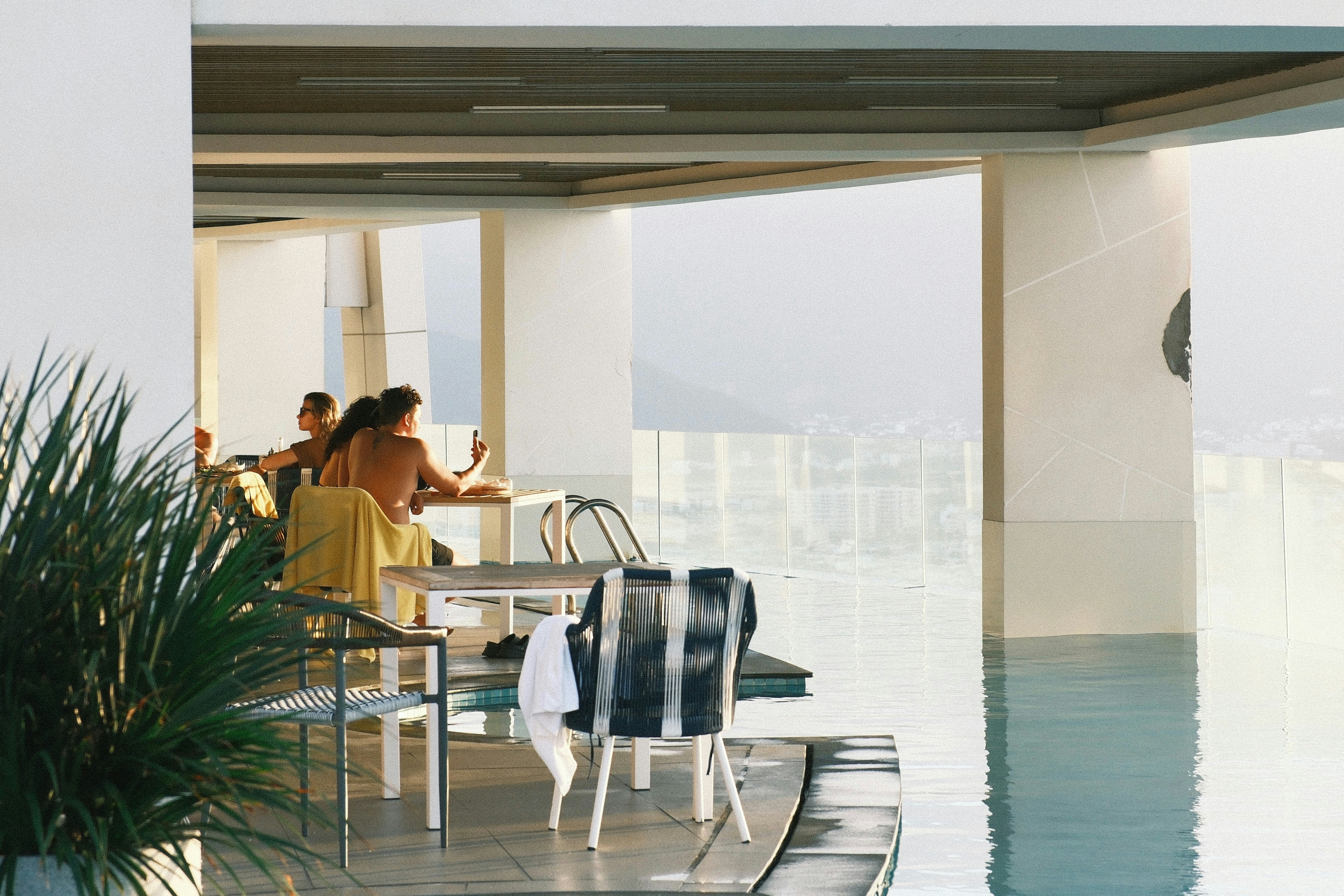 a group of people sitting at a table next to a pool