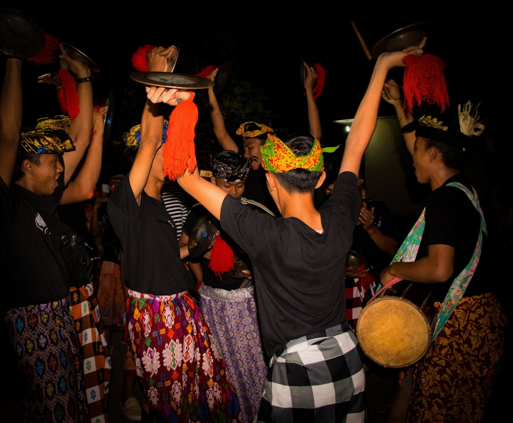 a group of people standing around each other holding hats