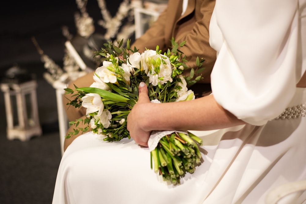 a bride holding a bouquet of white flowers