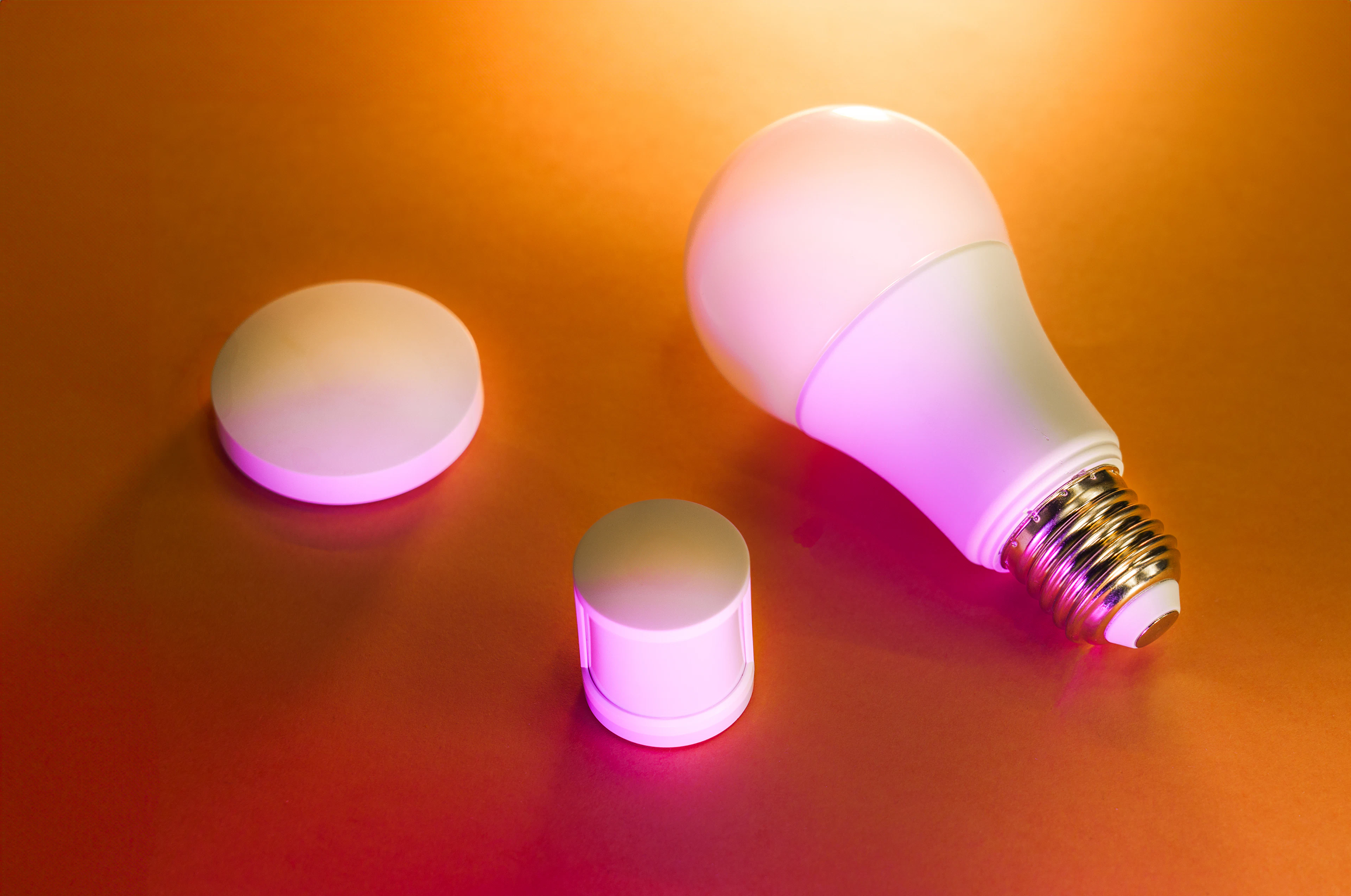 Smart light bulbs glowing in warm pink and orange tones