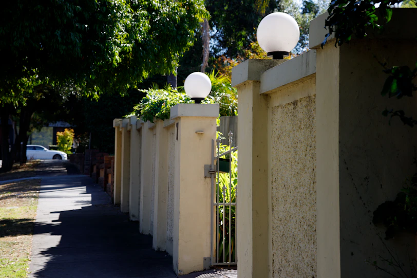 a street with a fence and two lamps on it