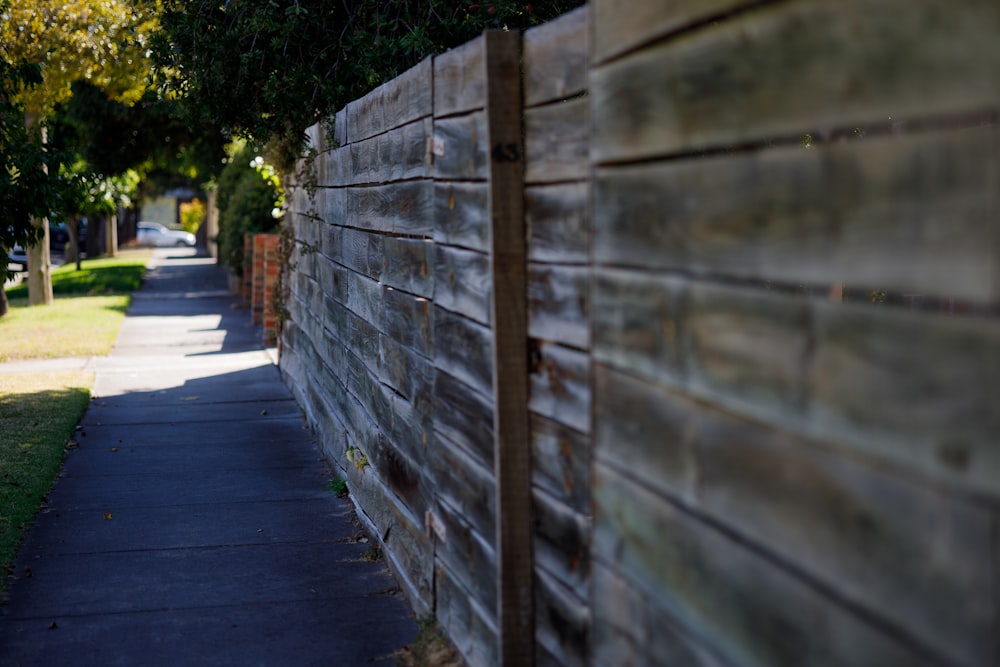 a long wooden fence next to a sidewalk