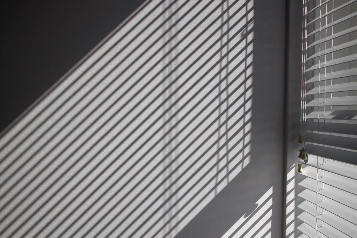 White venetian blinds with sunlight through the slats