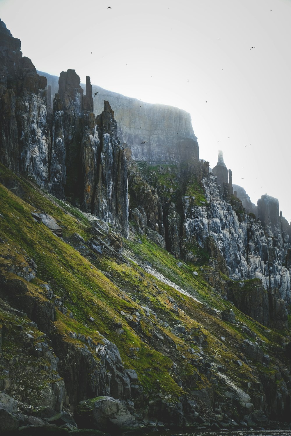 a rocky mountain with grass growing on it