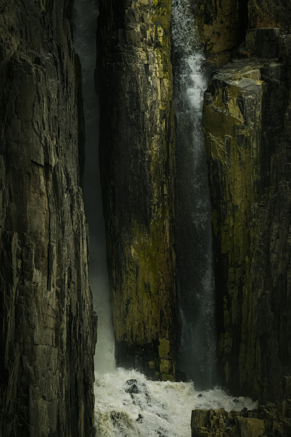 a waterfall is coming out of the rocks into the water
