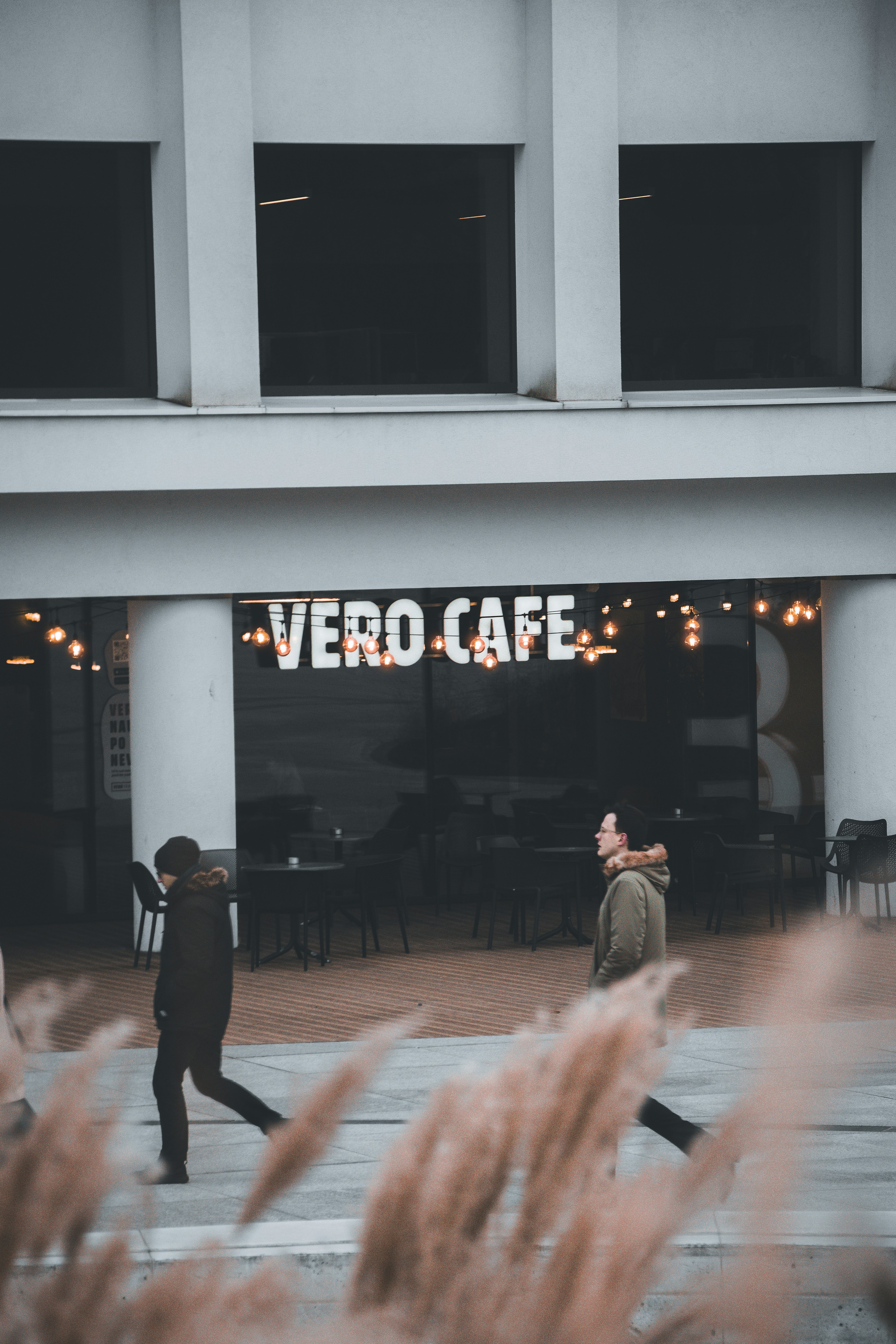um casal de pessoas caminhando em frente a um prédio