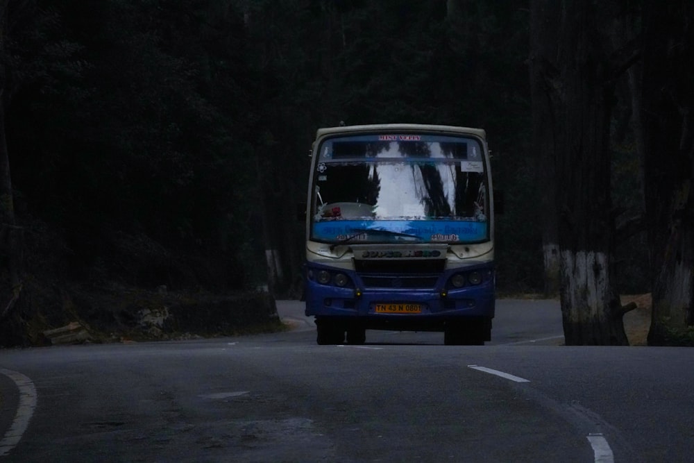 a blue and white bus driving down a road