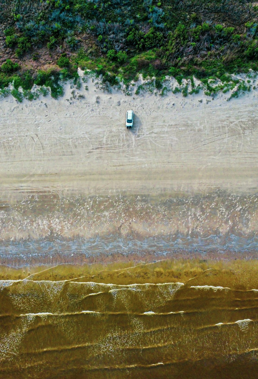 an aerial view of a beach with a boat in the water