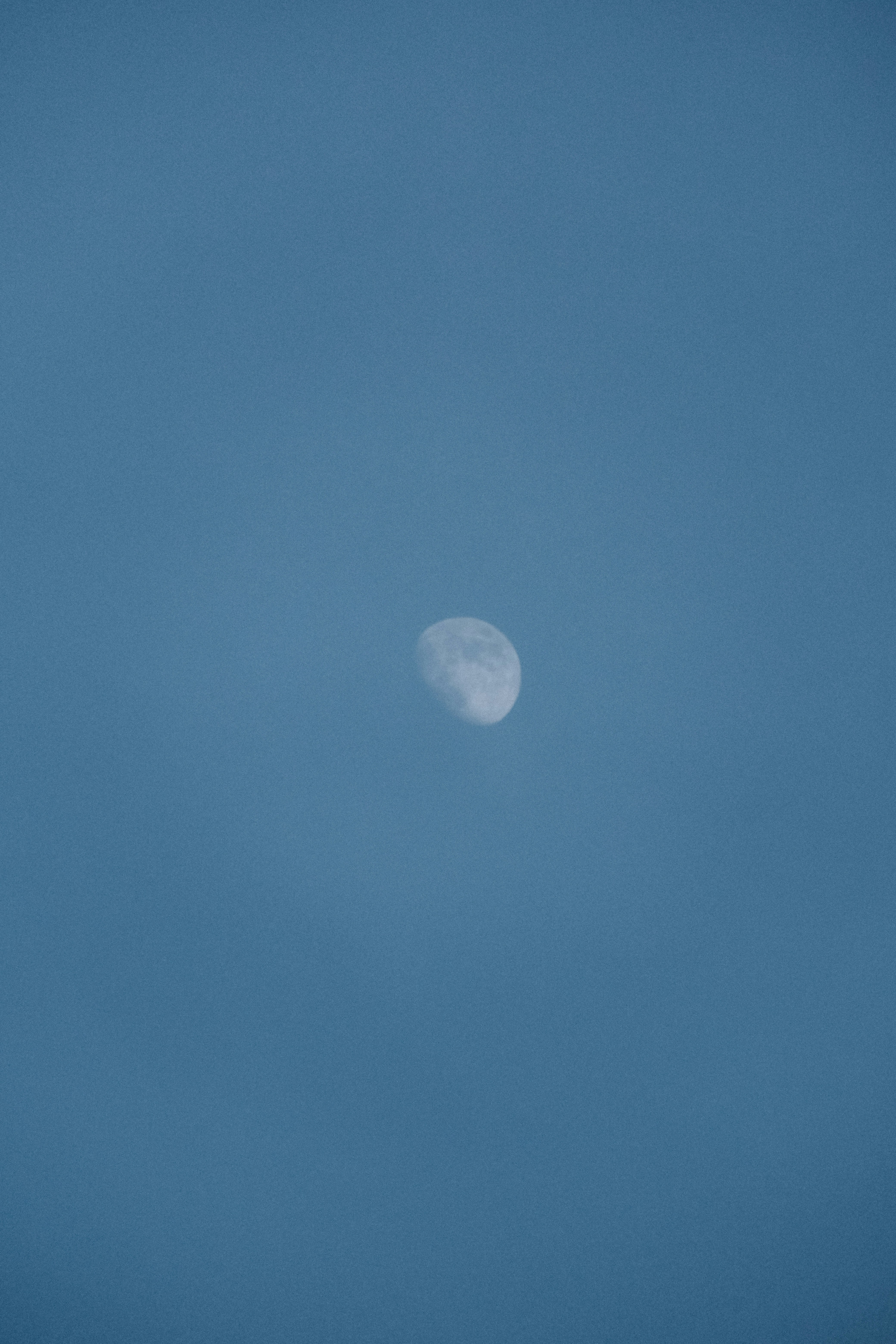 a plane flying in the sky with the moon in the distance