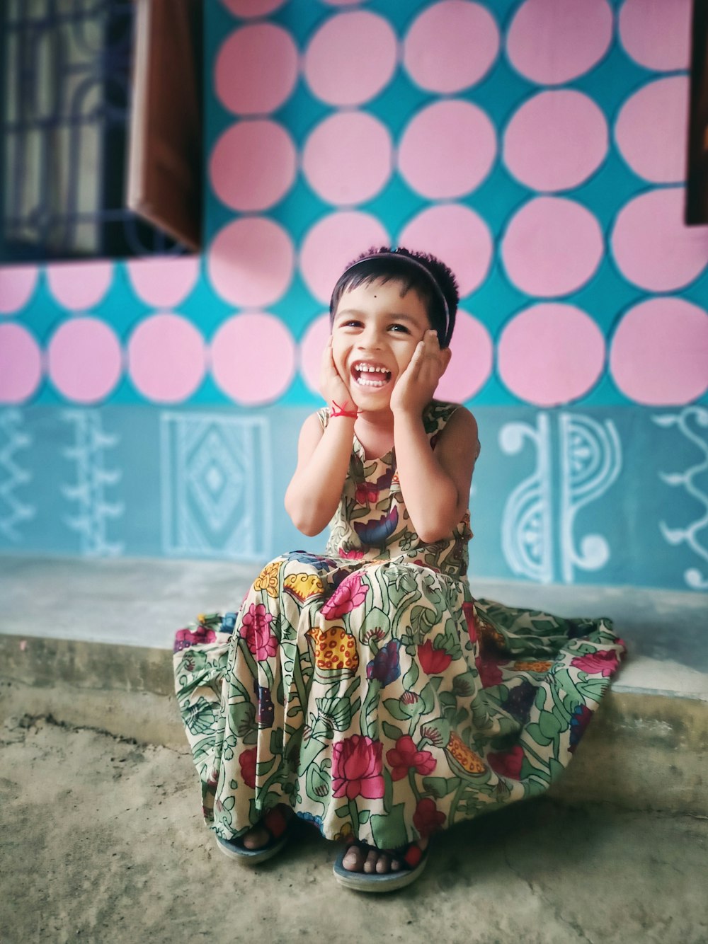 a little girl sitting on the ground laughing