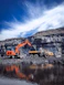 An orange excavator loading a yellow dump truck in a rocky quarry