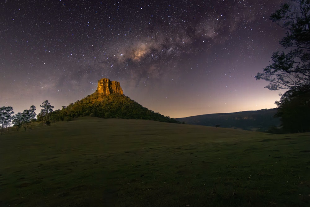 a night sky with stars above a mountain