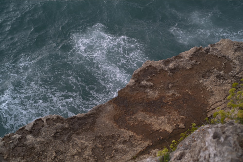 eine Person, die auf einer Klippe neben dem Meer steht