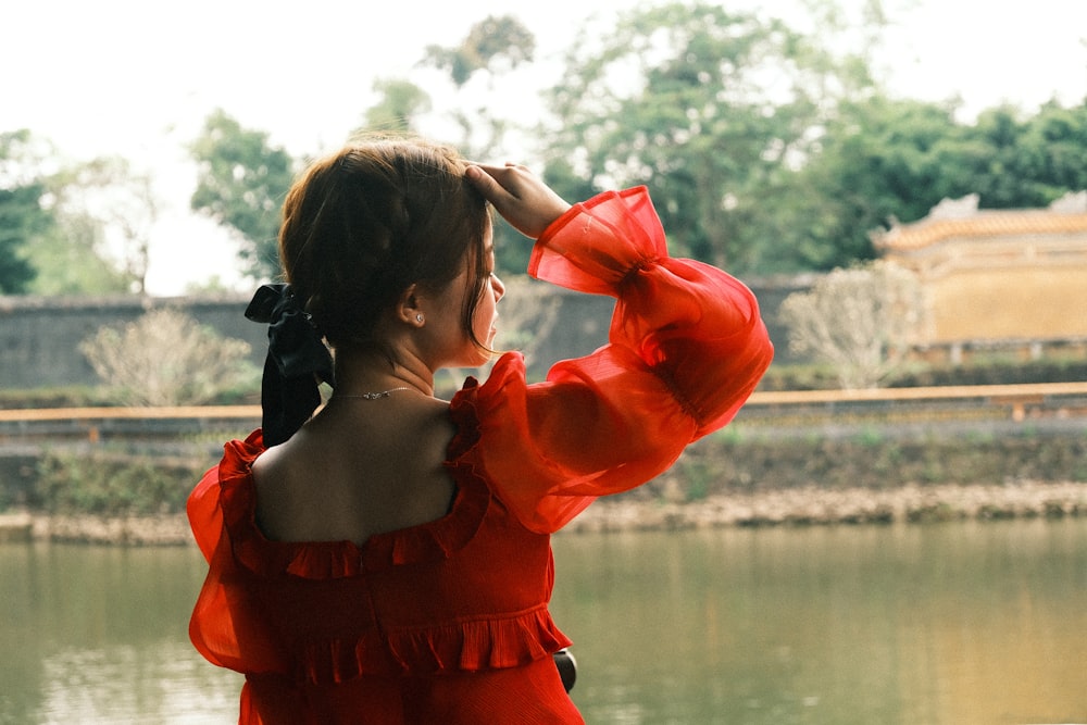 a woman in a red dress looking out over a lake