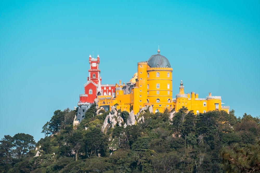 a yellow and red castle sitting on top of a hill