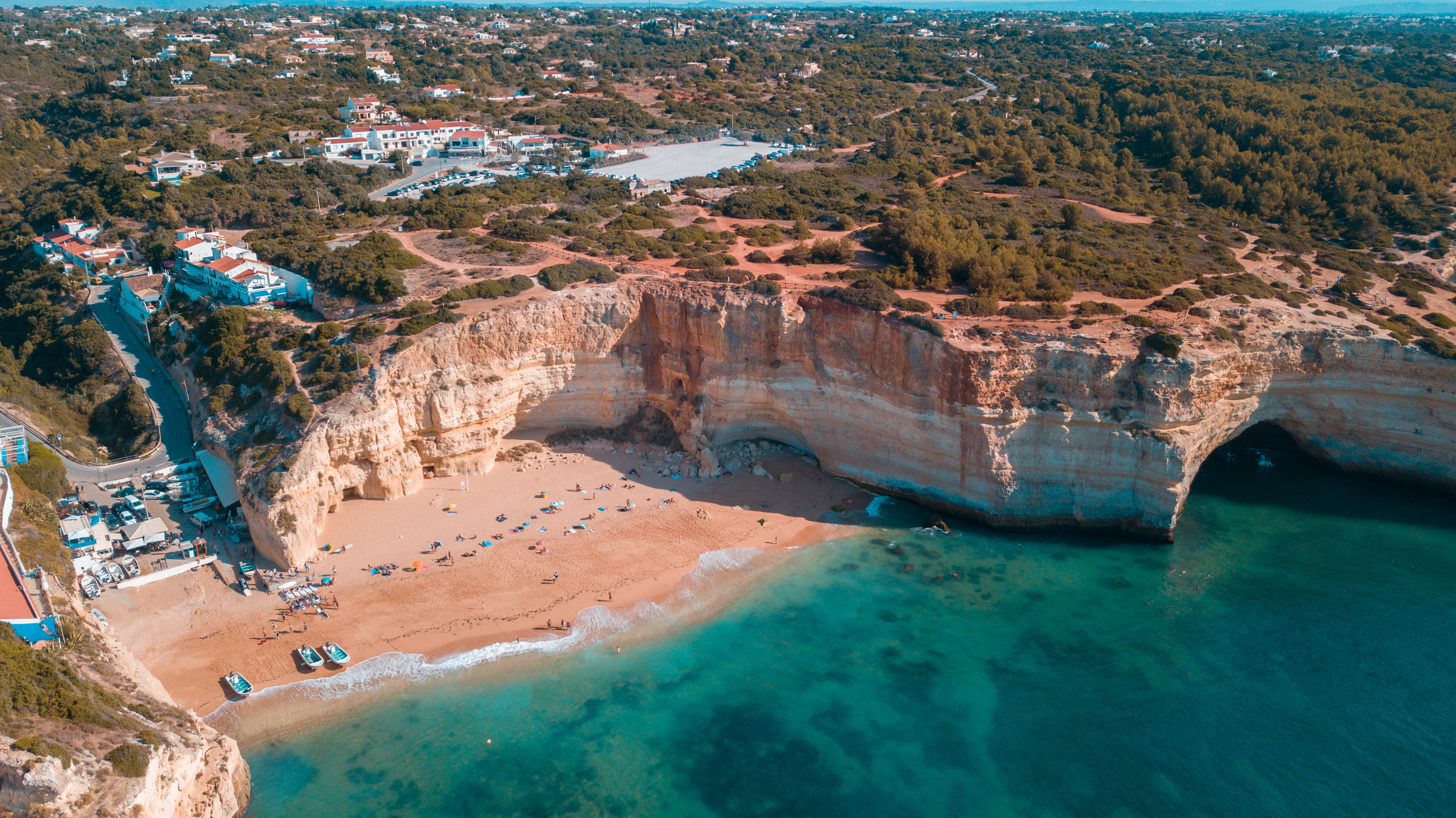 A beach below golden cliffs on the coast from the air, the scenery of cycling the Algarve