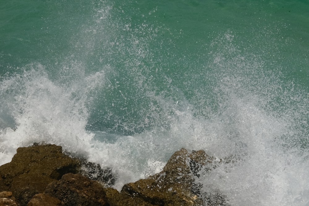 a wave crashes against the rocks at the beach
