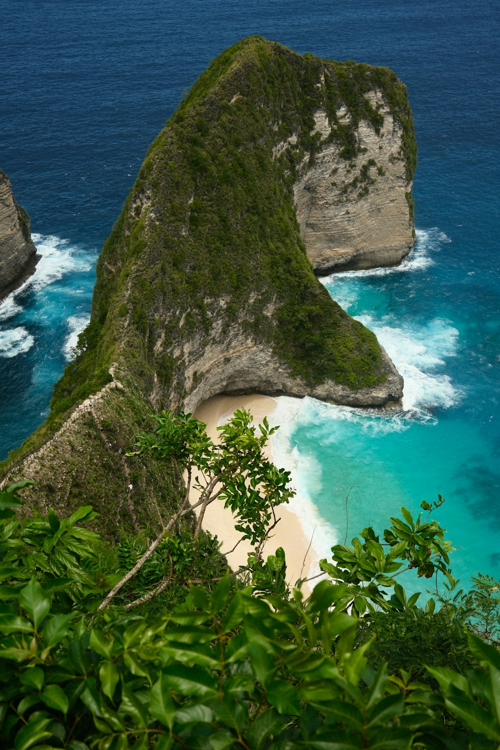 a beach with a large rock sticking out of the water